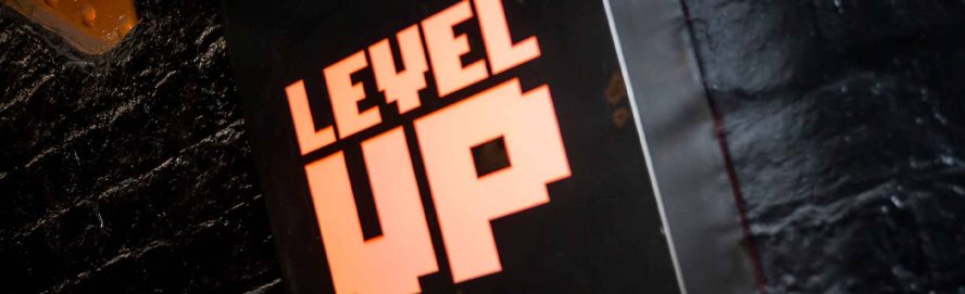 A neon 'Level Up' wall sign at the ArCains arcade bar in Liverpool.