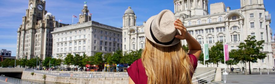 Woman tourist looking up at the Three Graces buildings in Liverpool.