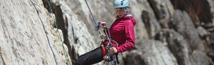 Woman abseiling down a mountain cliff.